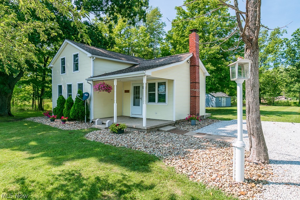 View of front of property featuring an outdoor structure, a porch, and a front lawn