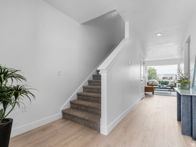 738 West 2840 South, Unit 6 Nibley, UT 84321 - Photo 6 of 23 Entryway featuring light wood-finish flooring, white baseboards, and a carpeted staircase with white banister