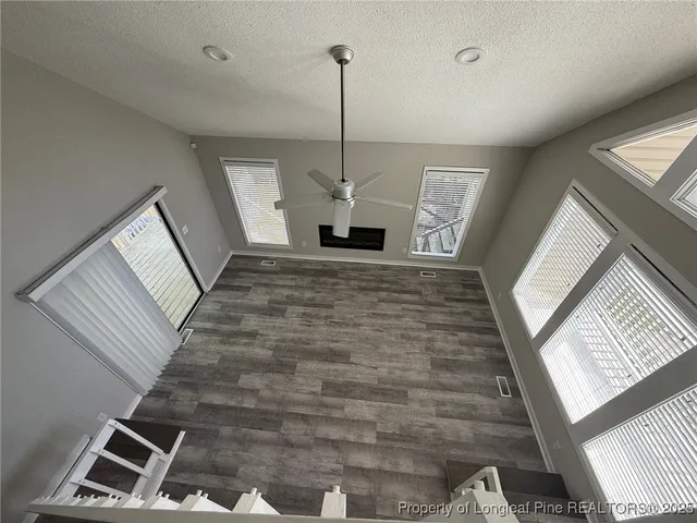 a view of a hallway to room with wooden floor and window