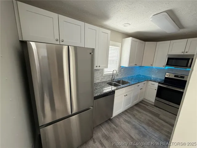 a kitchen with stainless steel appliances granite countertop a refrigerator a microwave a sink and cabinets