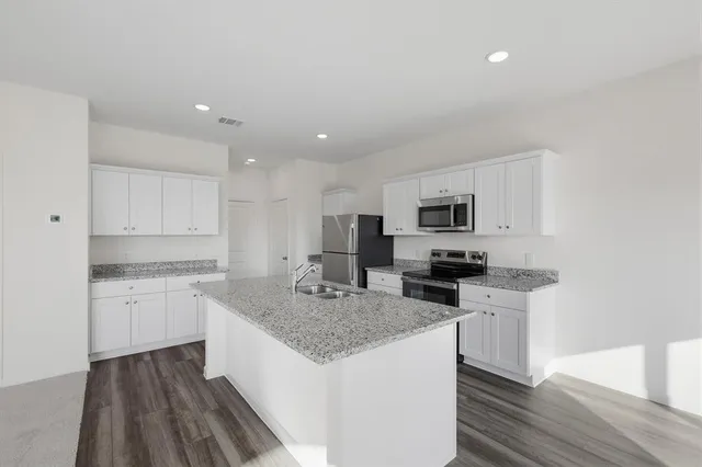 a kitchen with stainless steel appliances granite countertop a sink stove microwave and refrigerator