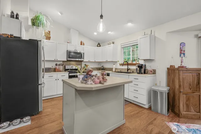 a kitchen with kitchen island stainless steel appliances a sink a stove a refrigerator cabinets and living room view