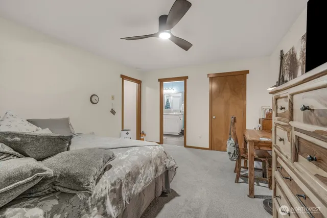 a spacious bedroom with a bed and a flat tv screen on the dresser