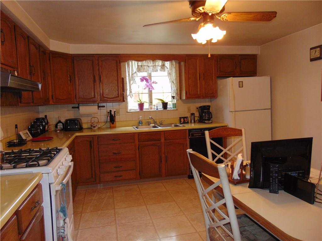 5569 Aiken Road McKees Rocks, PA 15136 - Photo 11 of 24 a kitchen with a refrigerator a stove a microwave and wooden cabinets