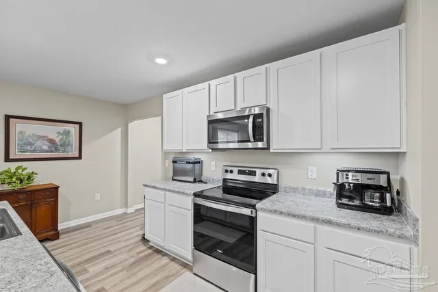 a kitchen with stainless steel appliances granite countertop white cabinets and a stove top oven