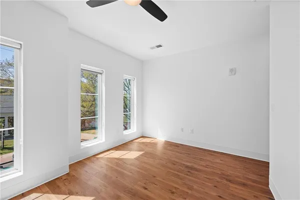 an empty room with wooden floor cabinet and windows