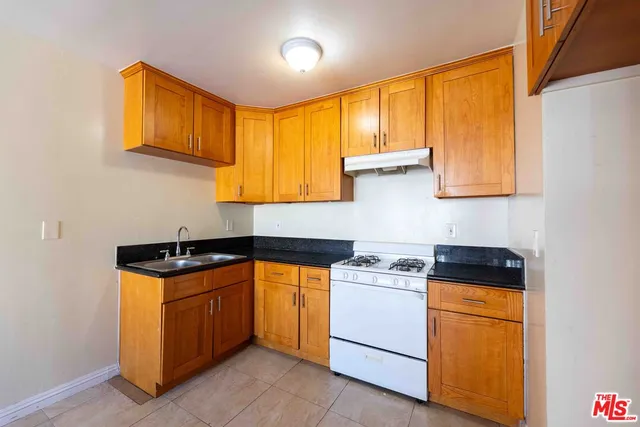 a kitchen with stainless steel appliances granite countertop wooden cabinets stove top oven and sink