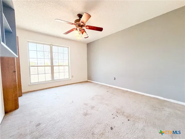 an empty room with windows and fan