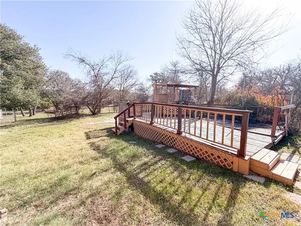 a view of a yard with wooden fence and large trees
