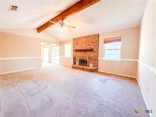 an empty room with windows and fireplace