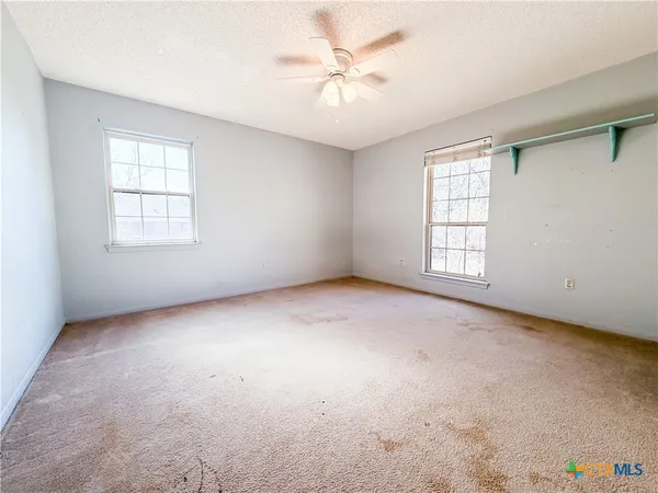 an empty room with windows and ceiling fan