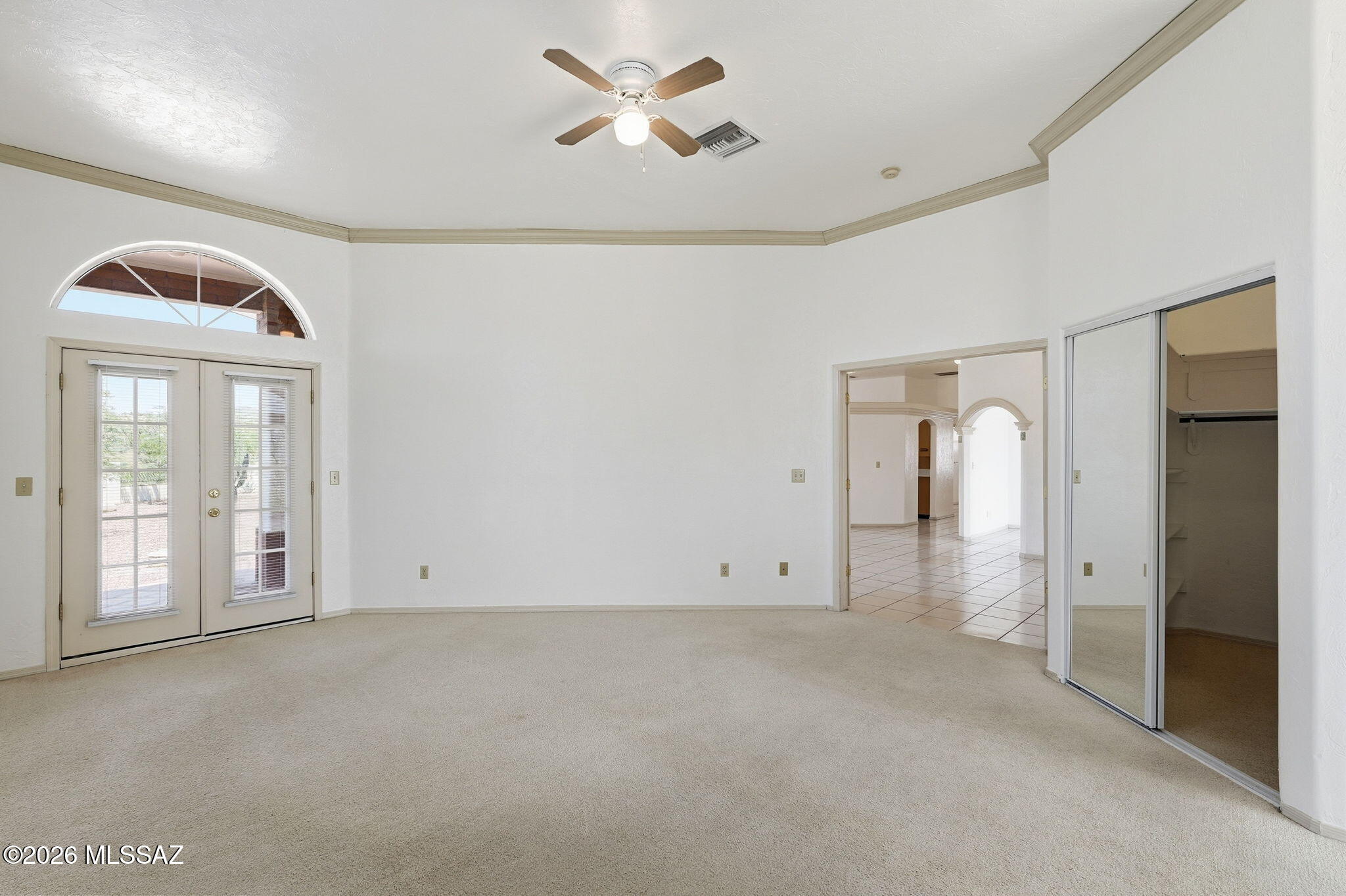 1242 Vista Court Rio Rico, AZ 85648 - Photo 18 of 51 The generously sized primary bedroom provides plenty of room for oversized furniture while still maintaining a spacious and comfortable feel. Stylish French doors provide direct access to the backyard, making it easy to step outside and enjoy the fresh air and peaceful surroundings. Crown molding adds an elegant finishing touch, while a ceiling fan keeps the air comfortably circulating. Soft carpeting underfoot adds warmth and comfort, especially on those cooler mornings when you will appreciate not stepping onto a cold floor.
