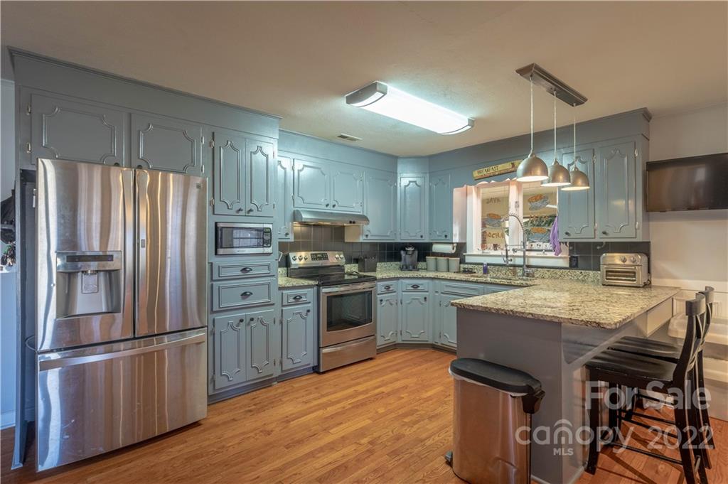 7680 Rhodhiss Road Connelly Springs, NC 28612 - Photo 5 of 25 a kitchen with granite countertop a refrigerator a stove a sink and a dining table with wooden floor