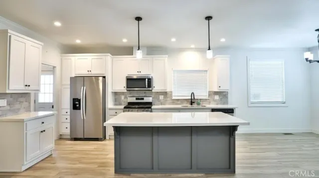 a kitchen with stainless steel appliances a sink a stove a refrigerator and cabinets