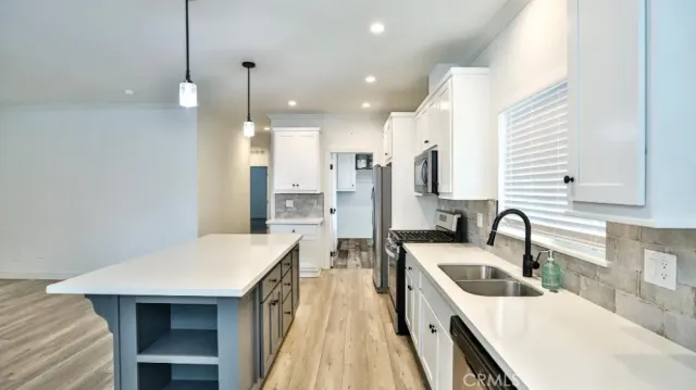 a kitchen with a sink a counter top space stainless steel appliances and cabinets