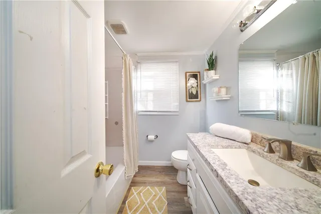 a bathroom with a granite countertop sink a toilet and shower