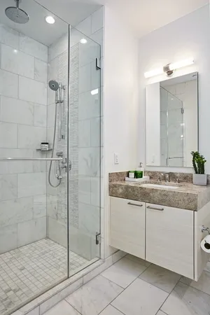 a bathroom with a granite countertop sink a mirror and shower