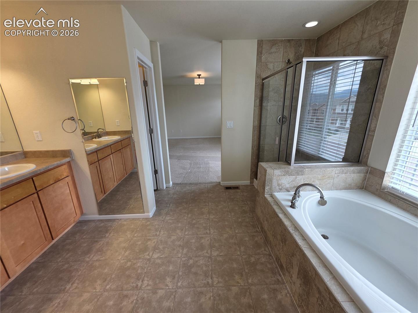 874 Diamond Rim Drive Colorado Springs, CO 80921 - Photo 17 of 28 Dual vanity with wood-finish cabinetry, tile flooring, built-in soaking tub, and a glass-enclosed shower