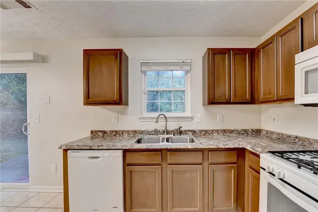 a kitchen with granite countertop a sink stove and cabinets