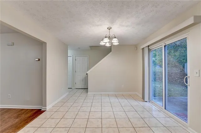 an empty room with chandelier fan and windows