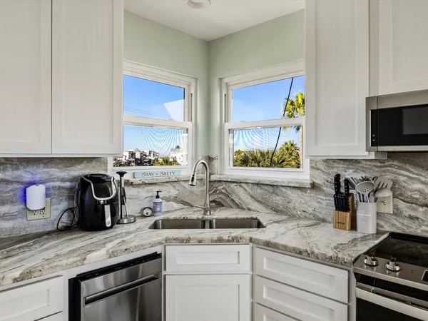 a kitchen with stainless steel appliances granite countertop a sink a stove and a wooden cabinets