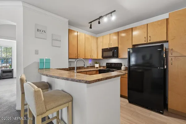 a kitchen with stainless steel appliances granite countertop a sink a stove a refrigerator a microwave a dining table and chairs with wooden floor