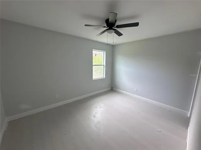 an empty room with a window and a fan