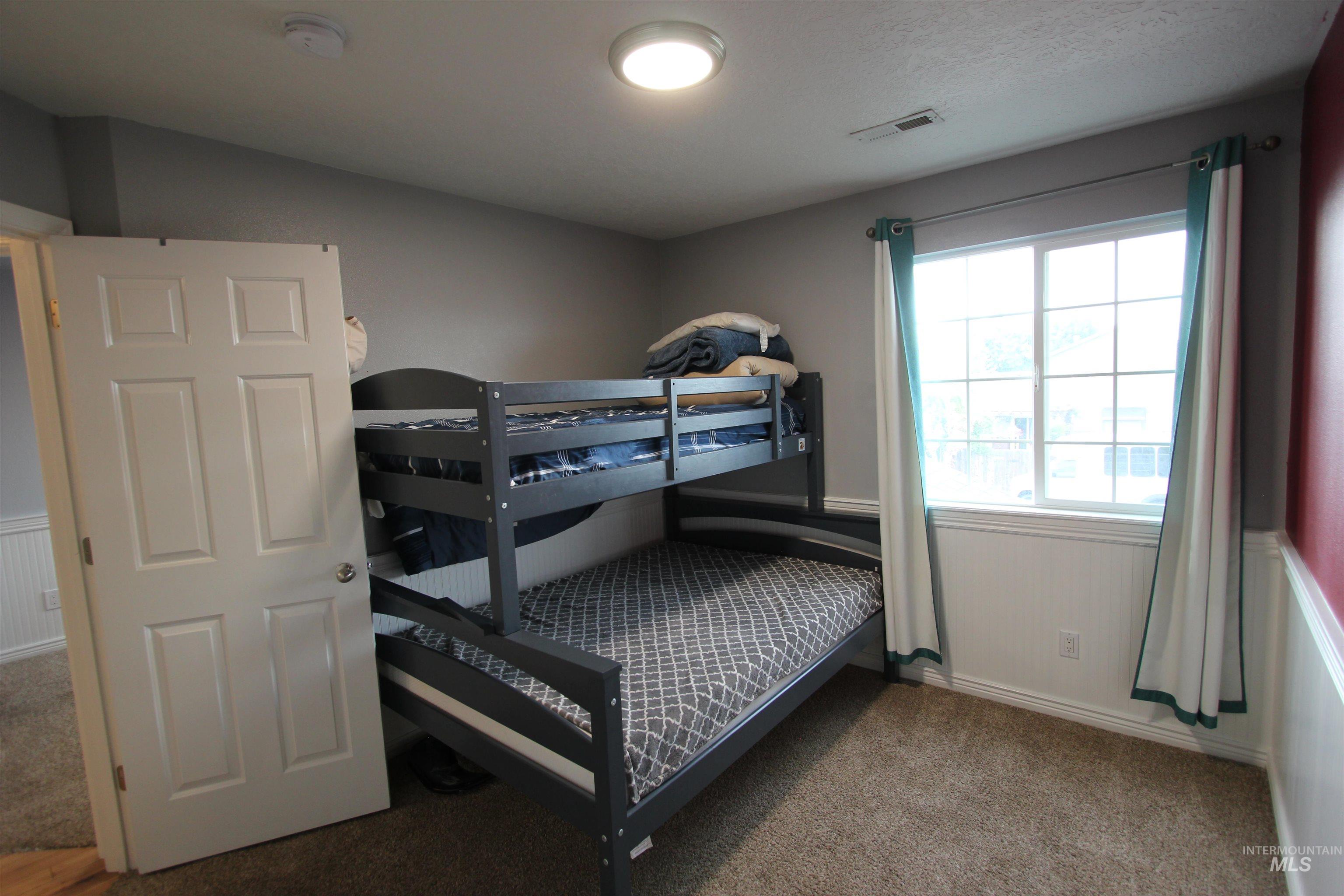 4816 Kadie Street Caldwell, ID 83607 - Photo 20 of 23 Room featuring gray walls with a partial red accent wall, white wainscoting, and carpet flooring