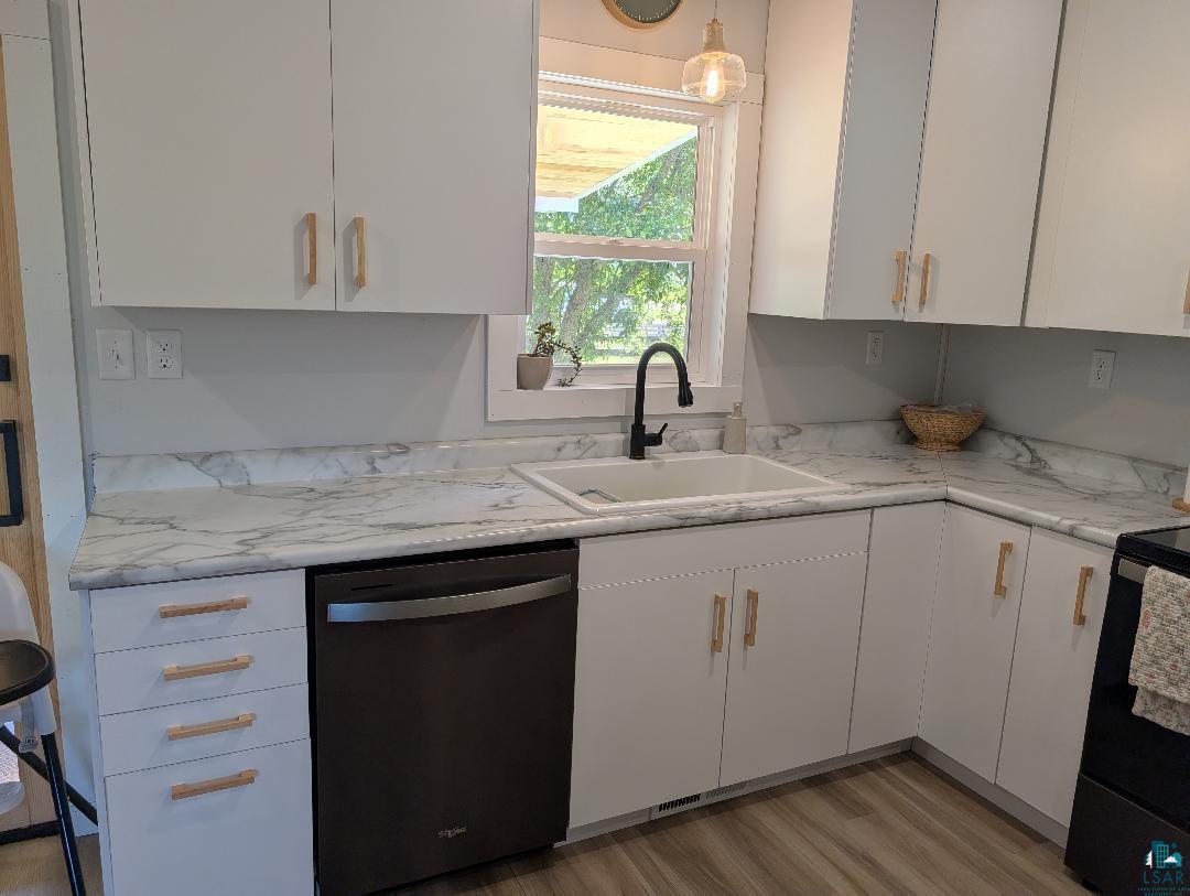 701 Drake Street Mellen, WI 54546 - Photo 17 of 27 Modern kitchen featuring white cabinetry with wooden pull handles, marbled countertops, a matte black gooseneck faucet, a white basin sink, and wood-finish flooring