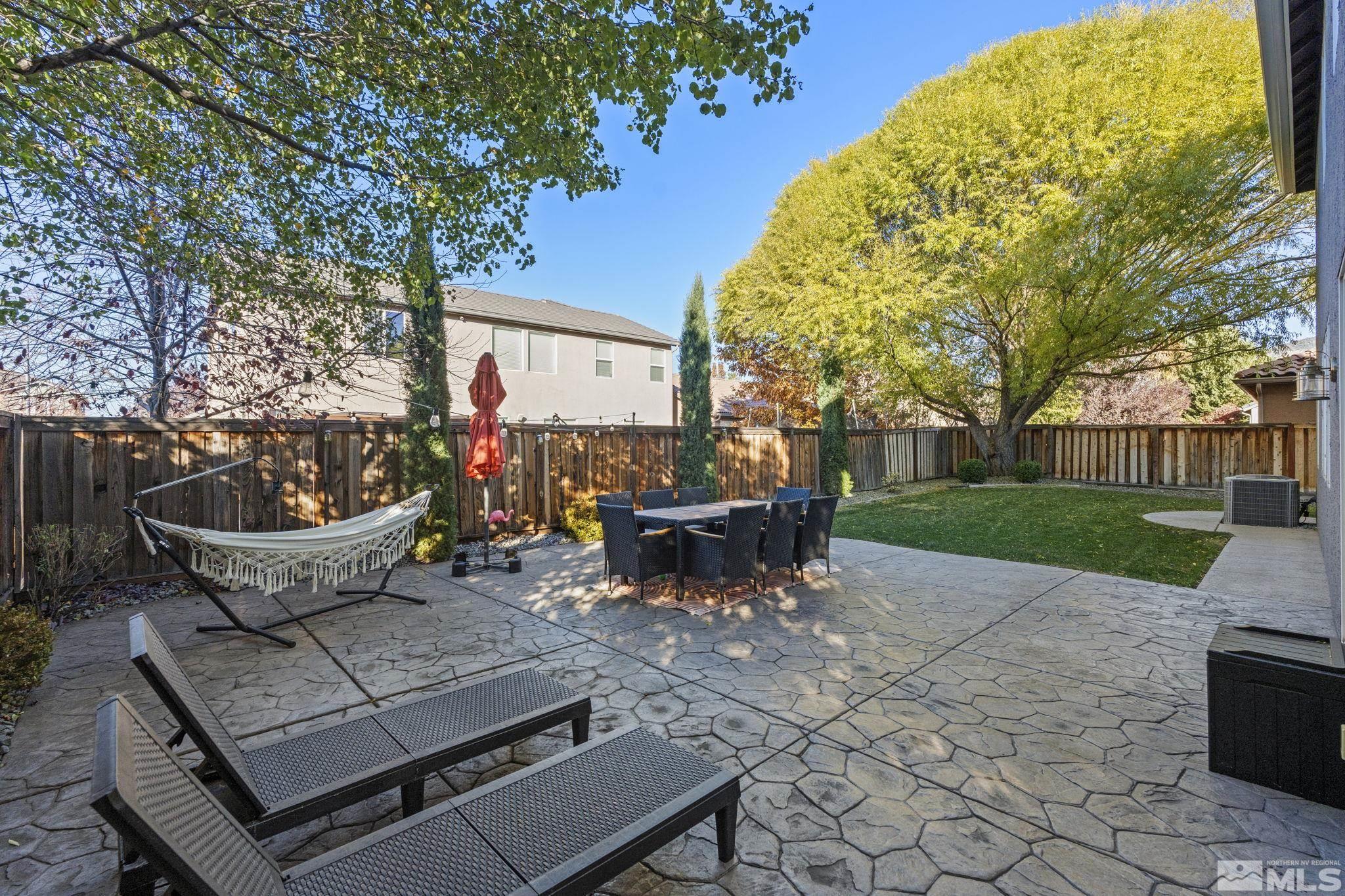 405 Teramo Court Reno, NV 89521 - Photo 34 of 40 a view of a patio with table and chairs and a barbeque with potted plants and large trees