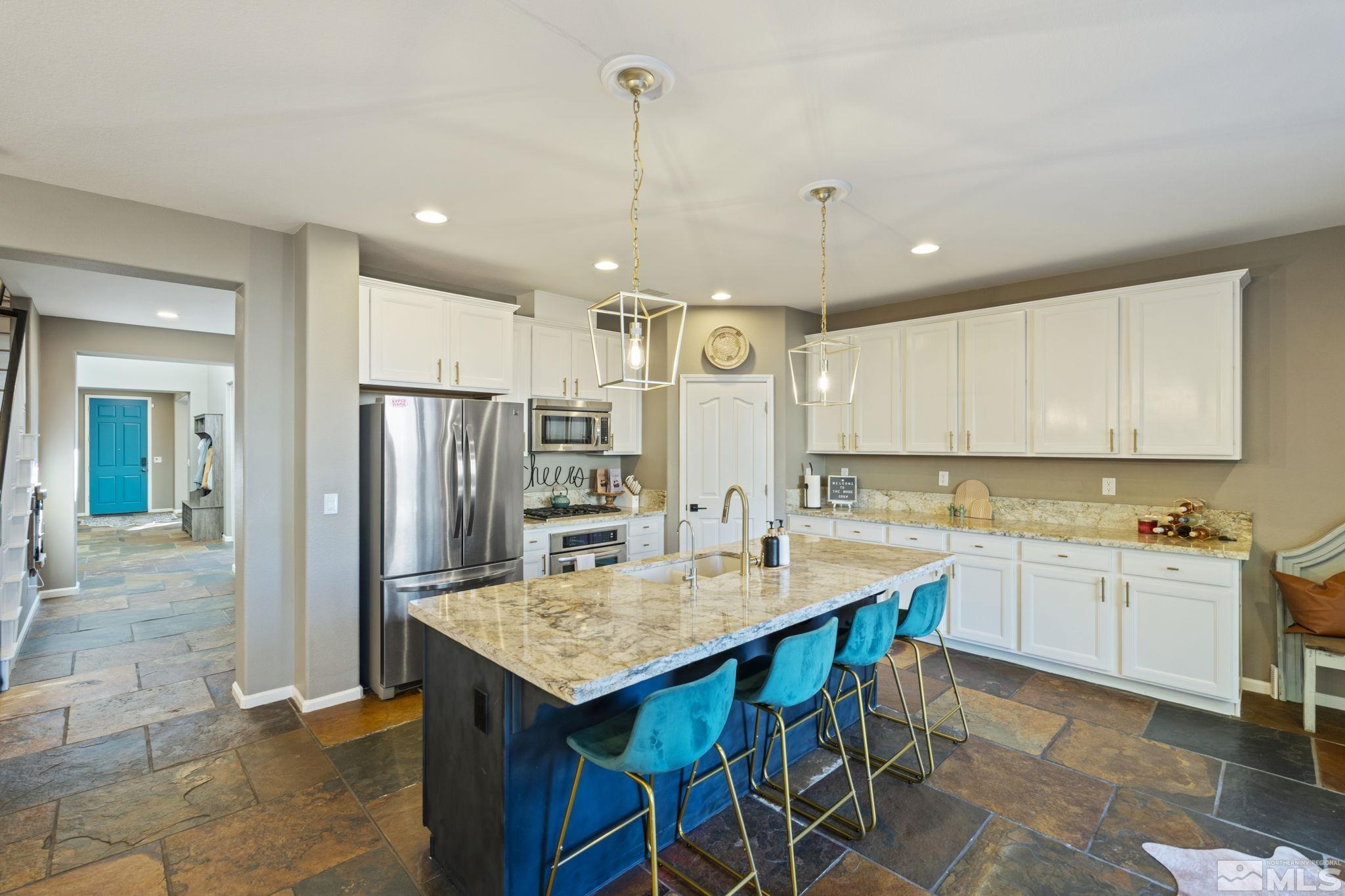 405 Teramo Court Reno, NV 89521 - Photo 7 of 40 a kitchen with stainless steel appliances kitchen island granite countertop a refrigerator a sink a stove and white cabinets with wooden floor