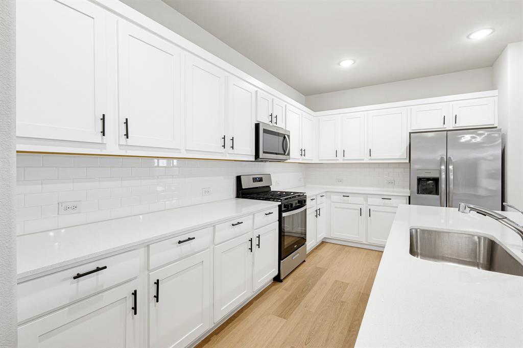 2108 Mossfield Lane Forney, TX 75126 - Photo 4 of 28 White cabinetry kitchen featuring stainless steel appliances, light wood-finish flooring, white subway tile backsplash, and recessed lighting