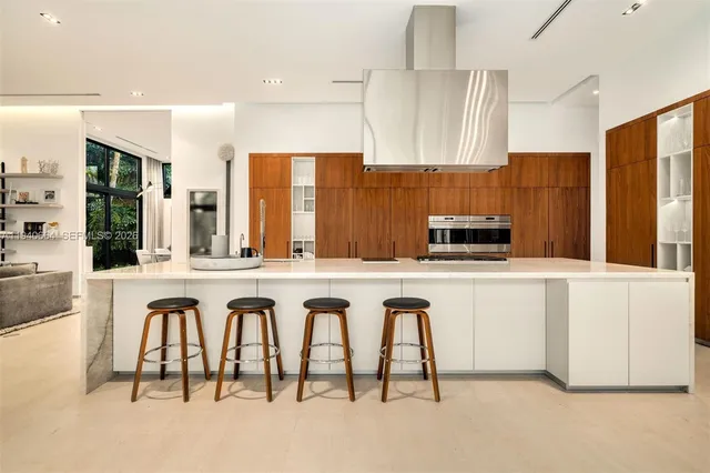 a white kitchen with stainless steel appliances granite countertop a stove a sink a refrigerator and white cabinets with wooden floor