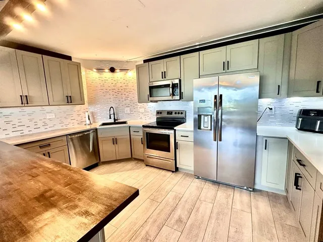 a kitchen with stainless steel appliances white cabinets and wooden floors