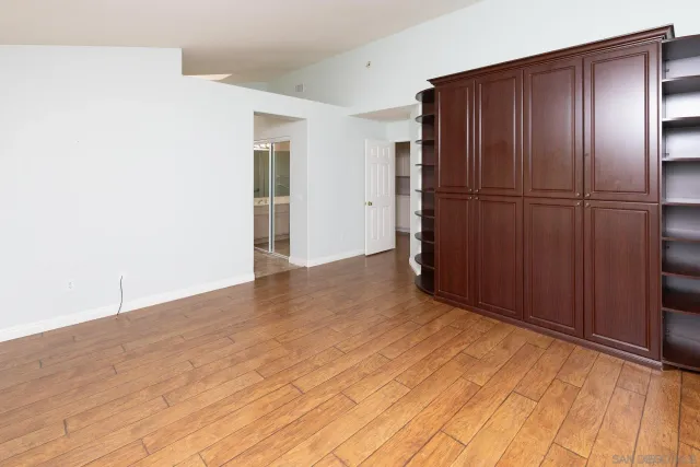 a view of an empty room with wooden floor and cabinet