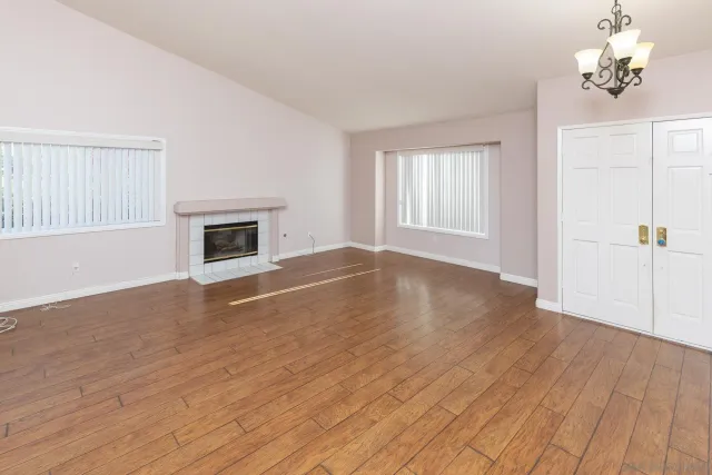 an empty room with wooden floor fireplace and windows