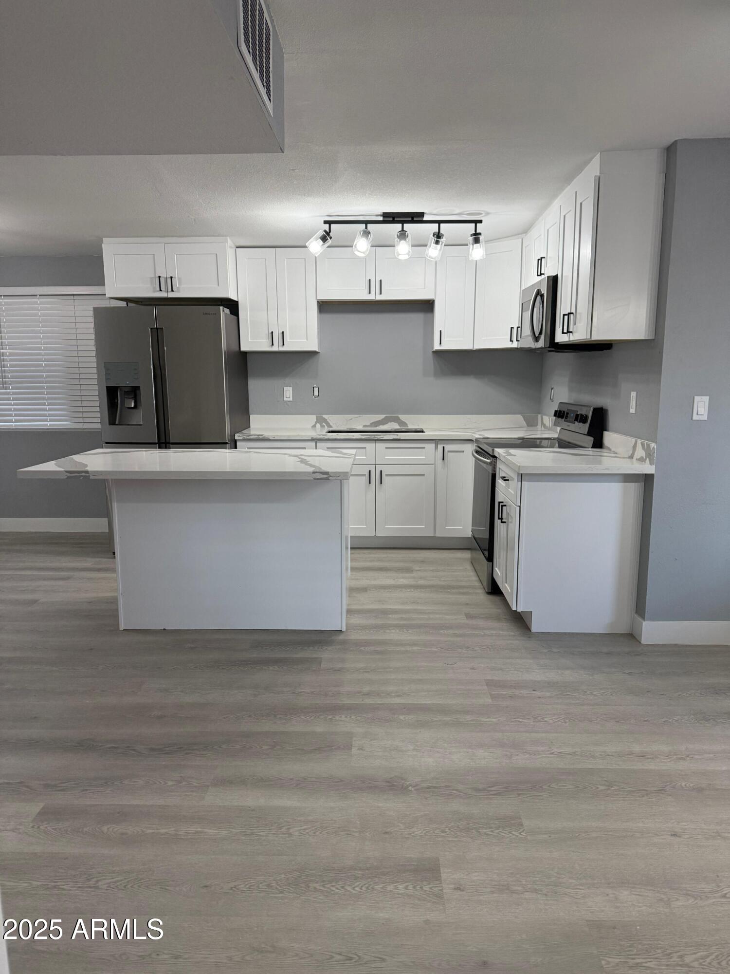 3619 West Griswold Road Phoenix, AZ 85051 - Photo 11 of 36 a kitchen with stainless steel appliances granite countertop a stove top oven a sink a refrigerator and white cabinets