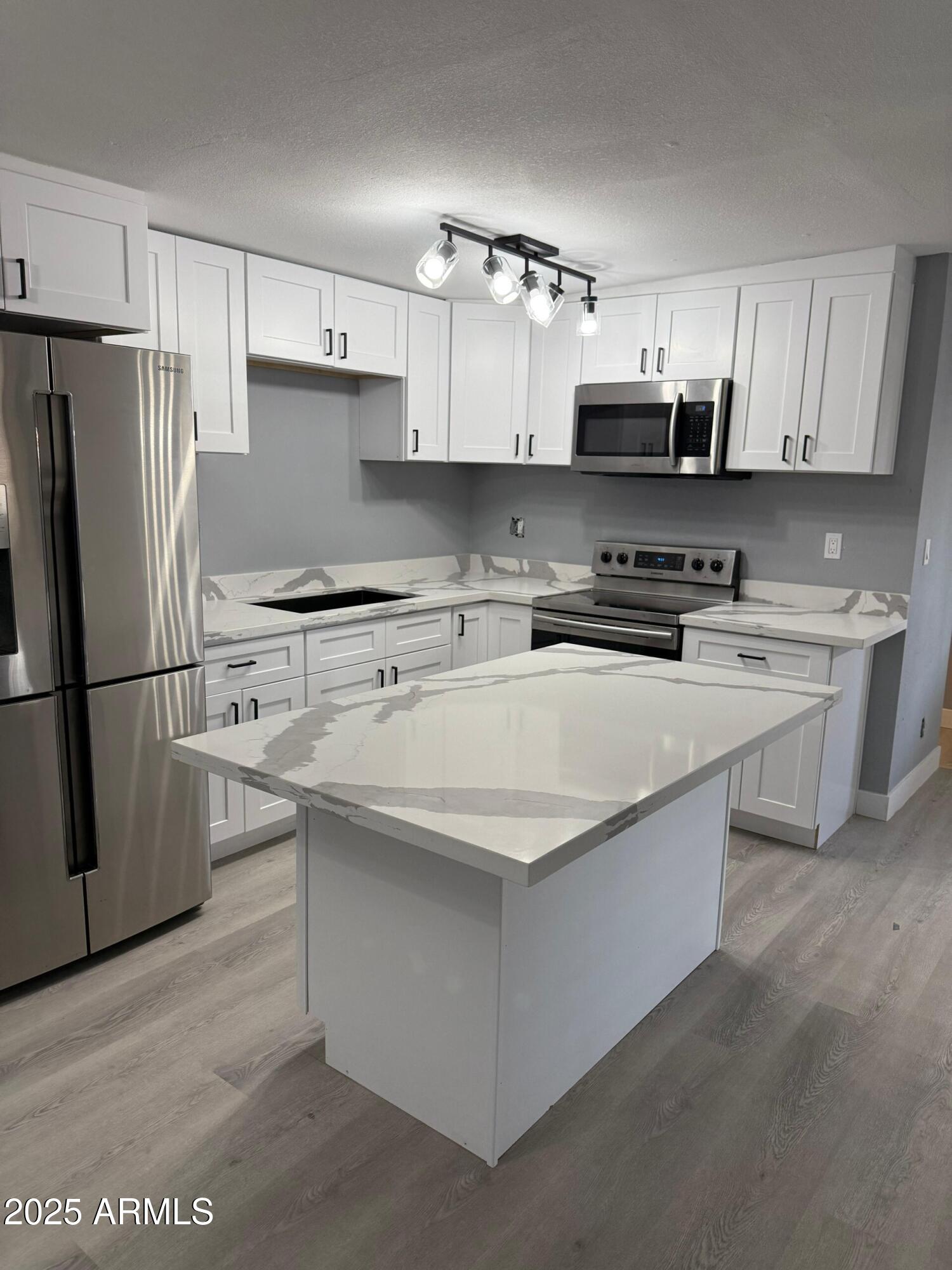 3619 West Griswold Road Phoenix, AZ 85051 - Photo 12 of 36 a kitchen with stainless steel appliances a sink a stove a microwave and cabinetry