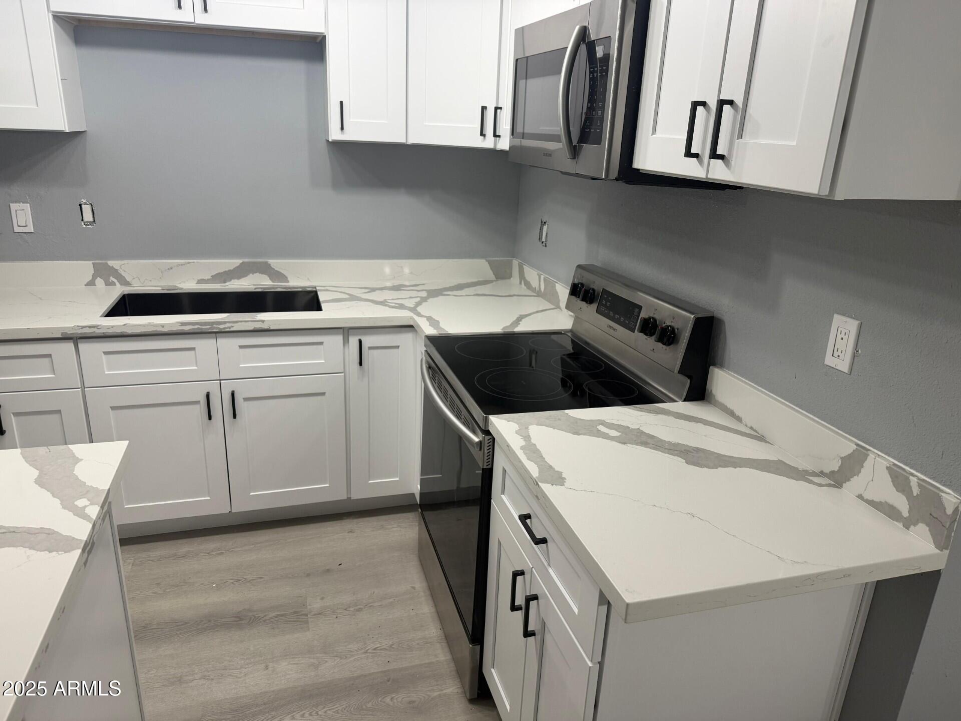 3619 West Griswold Road Phoenix, AZ 85051 - Photo 14 of 36 a kitchen with white cabinets and white appliances
