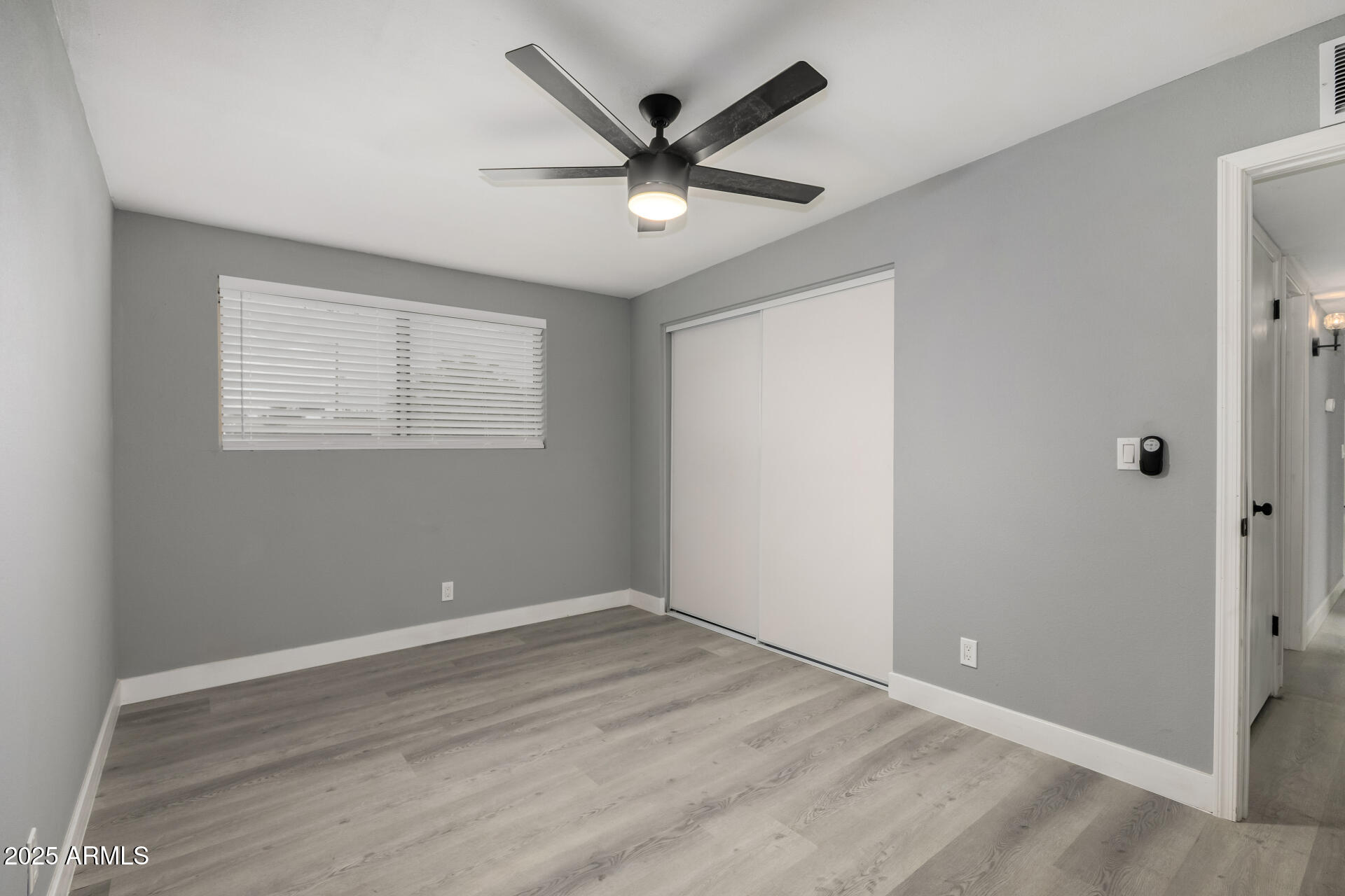 3619 West Griswold Road Phoenix, AZ 85051 - Photo 21 of 36 an empty room with wooden floor and ceiling fan