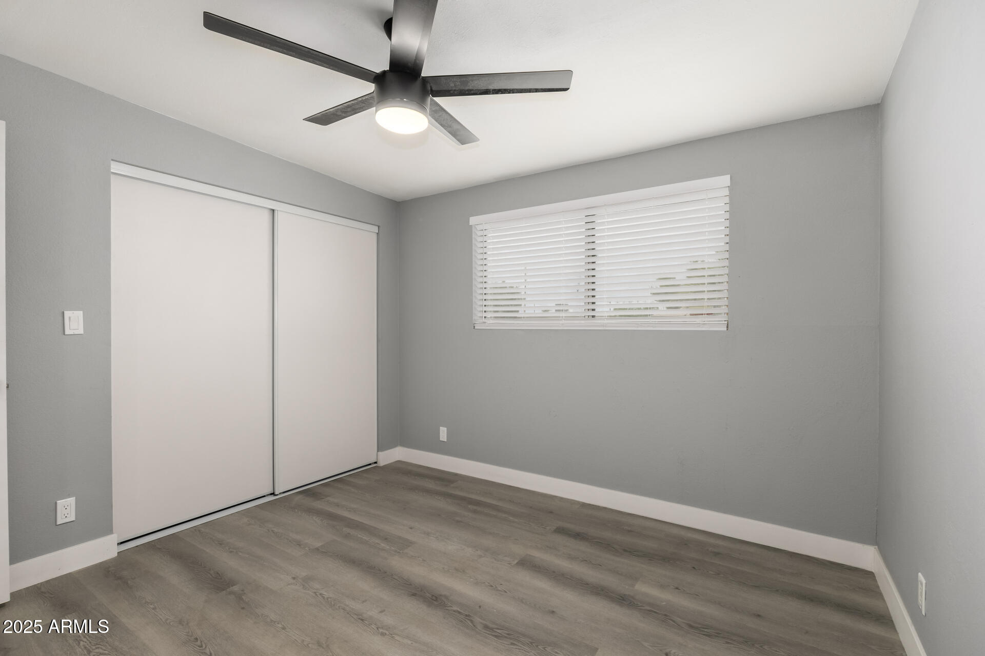 3619 West Griswold Road Phoenix, AZ 85051 - Photo 25 of 36 an empty room with wooden floor ceiling fan and windows