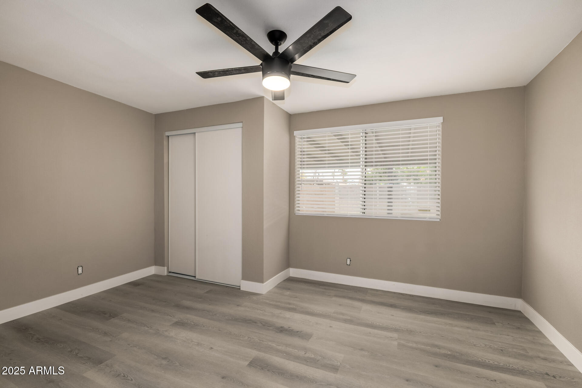 3619 West Griswold Road Phoenix, AZ 85051 - Photo 27 of 36 an empty room with wooden floor and windows