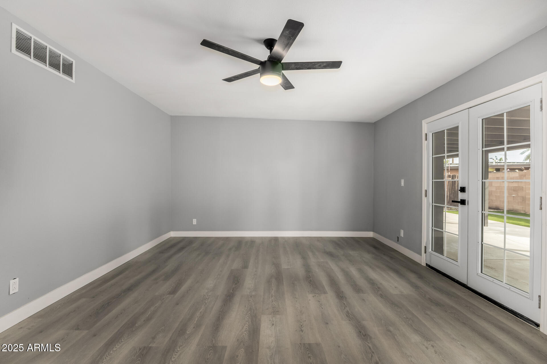 3619 West Griswold Road Phoenix, AZ 85051 - Photo 7 of 36 an empty room with wooden floor and windows