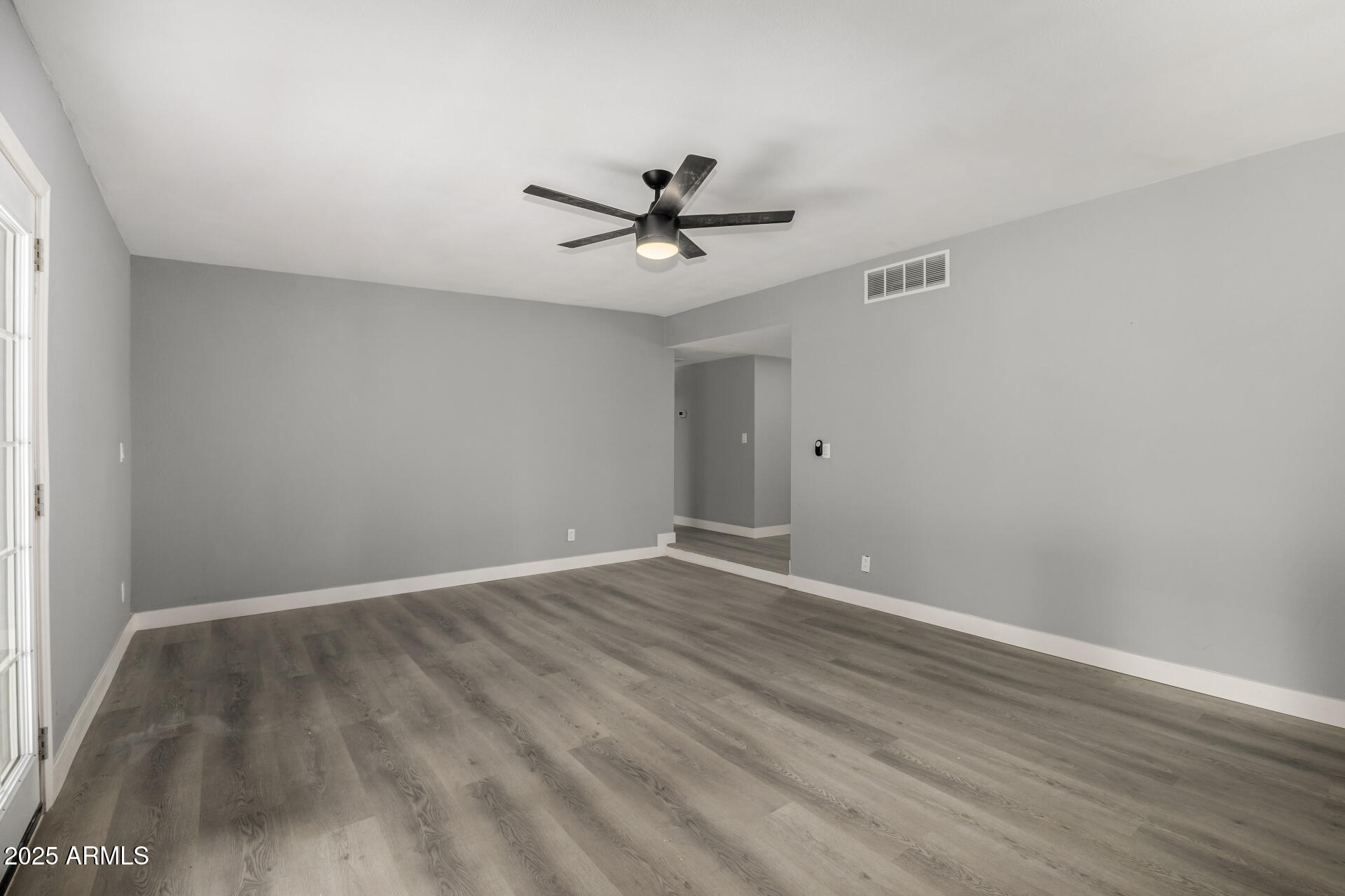 3619 West Griswold Road Phoenix, AZ 85051 - Photo 8 of 36 a view of a room with wooden floor and a ceiling fan