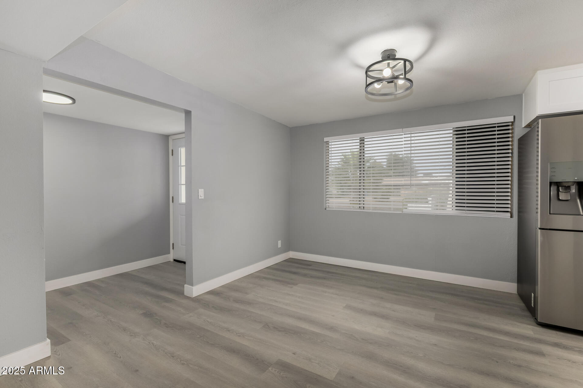 3619 West Griswold Road Phoenix, AZ 85051 - Photo 9 of 36 a view of empty room with wooden floor and window
