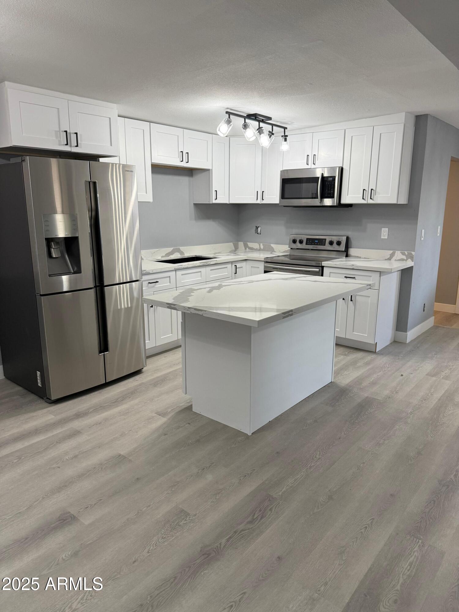 3619 West Griswold Road Phoenix, AZ 85051 - Photo 10 of 36 a kitchen with stainless steel appliances a sink a stove a refrigerator and cabinets