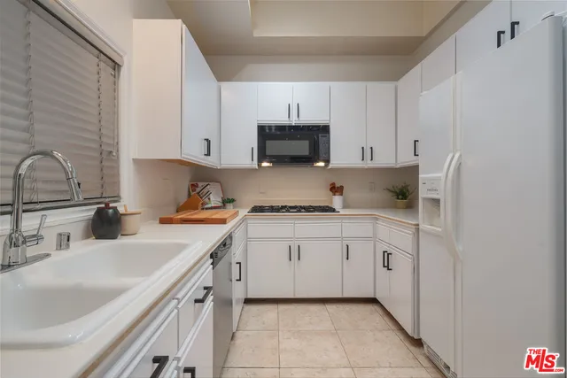 a kitchen with granite countertop white cabinets and white appliances