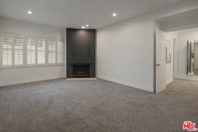 an empty room with windows and fireplace