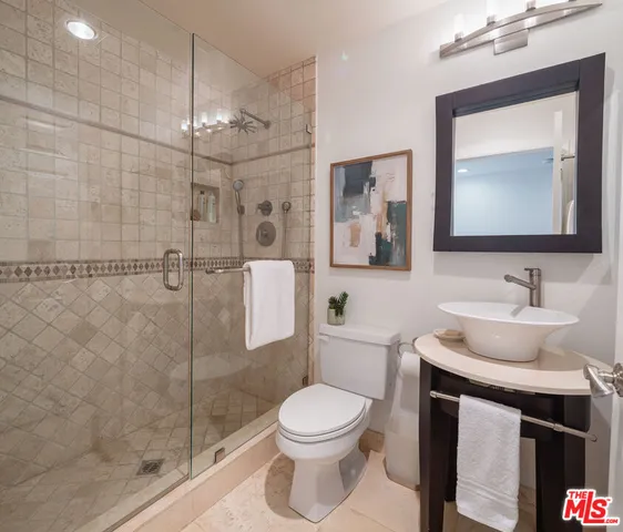 a bathroom with a toilet sink vanity granite and shower