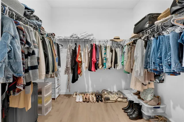 a view of walk in closet with clothes and shoes